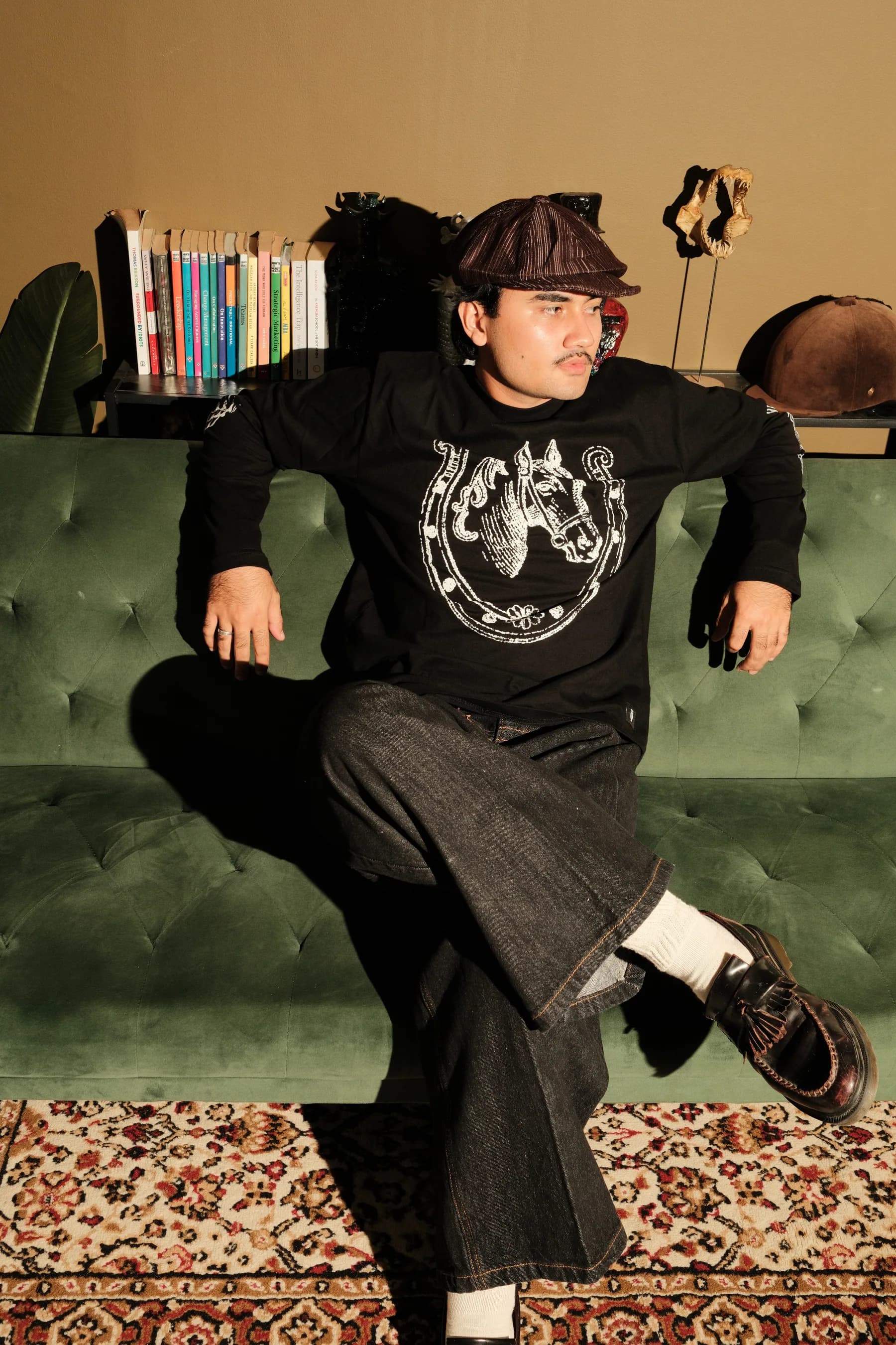 A model poses in a black TOHO outfit on a green sofa.