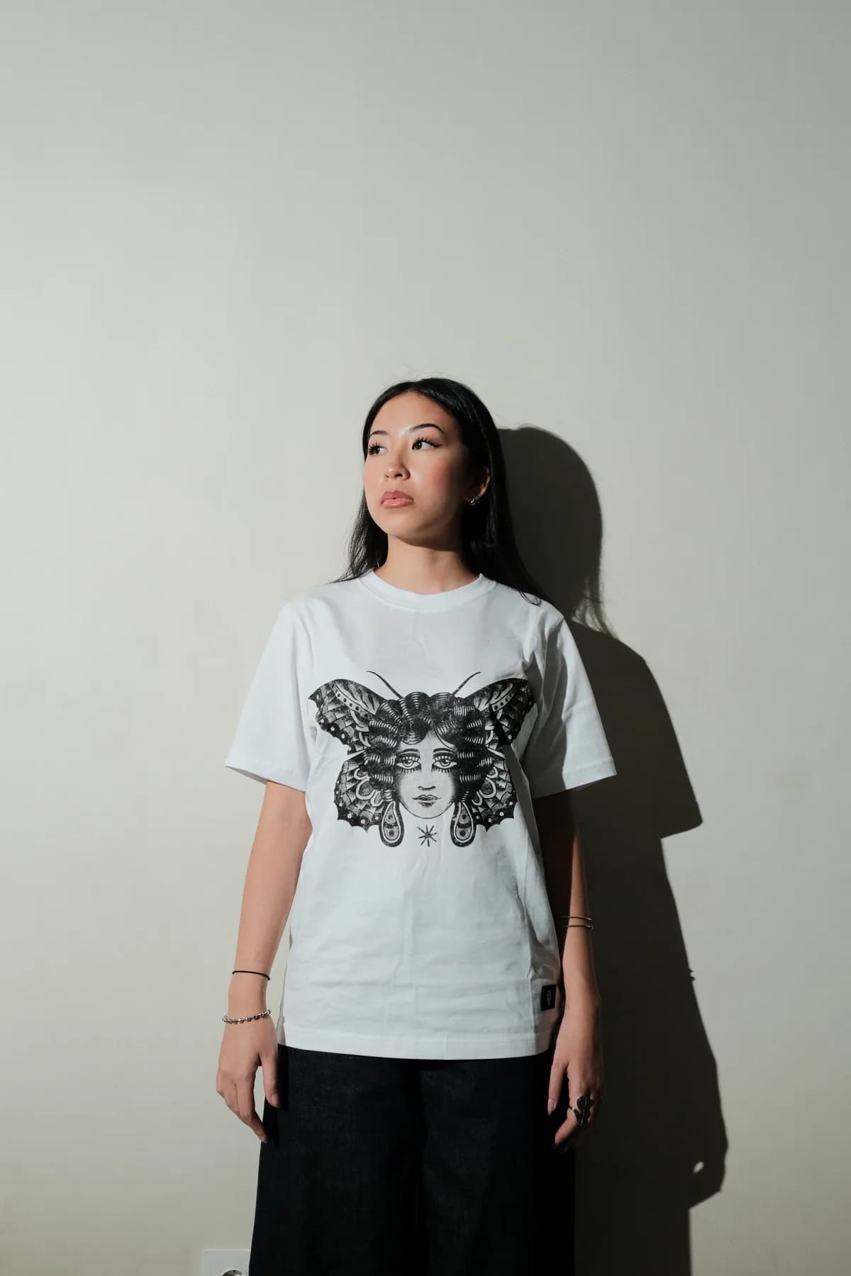 Model wearing the white Visage graphic T-shirt.